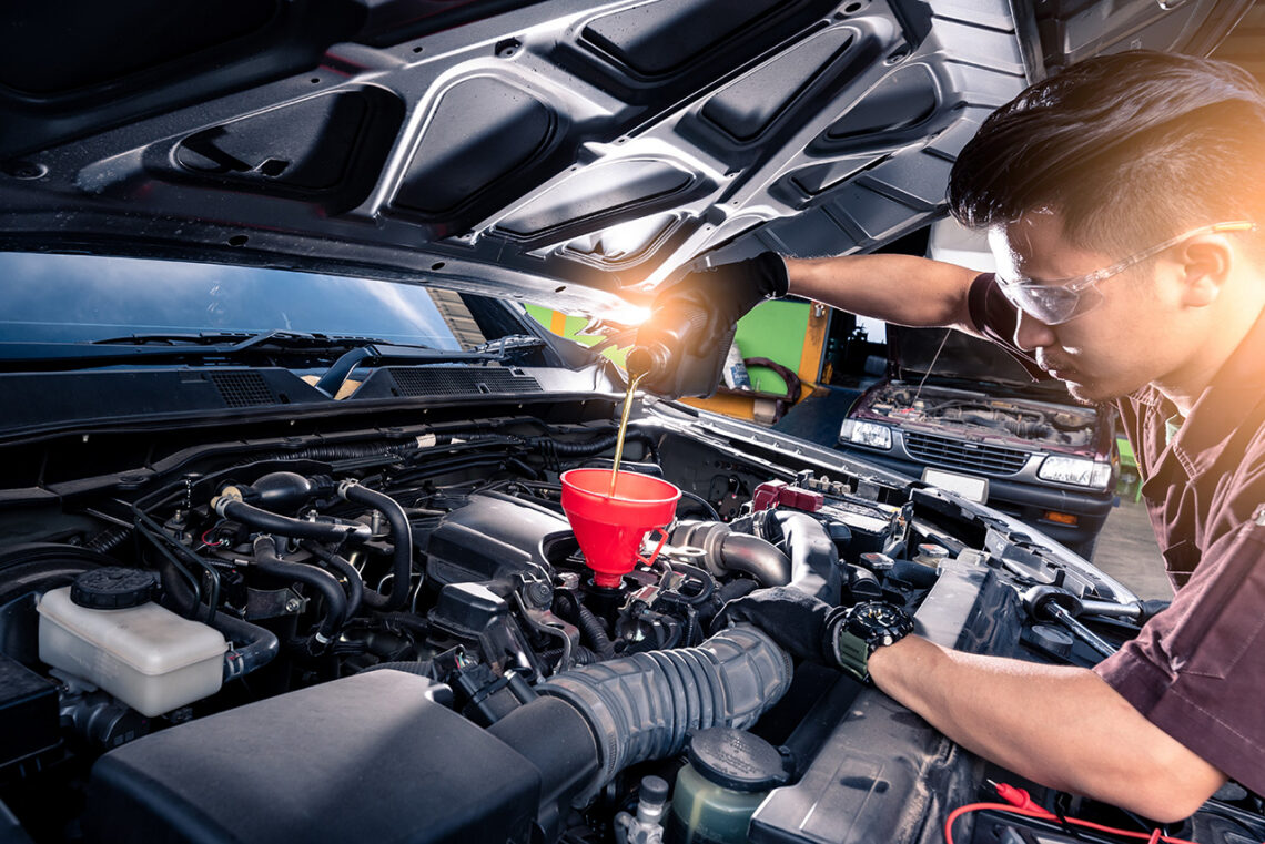Technician pouring oil into an engine