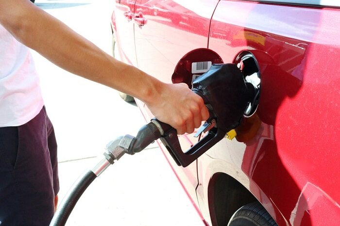 Close-up of pumping gas into a red car