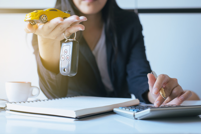 Woman dangling car keys holding a toy car